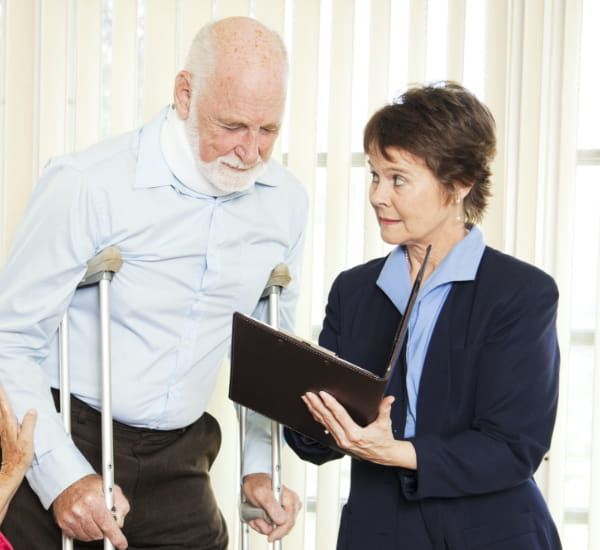 A picture of an elderly person with a cane while a female lawyer is showing some paper